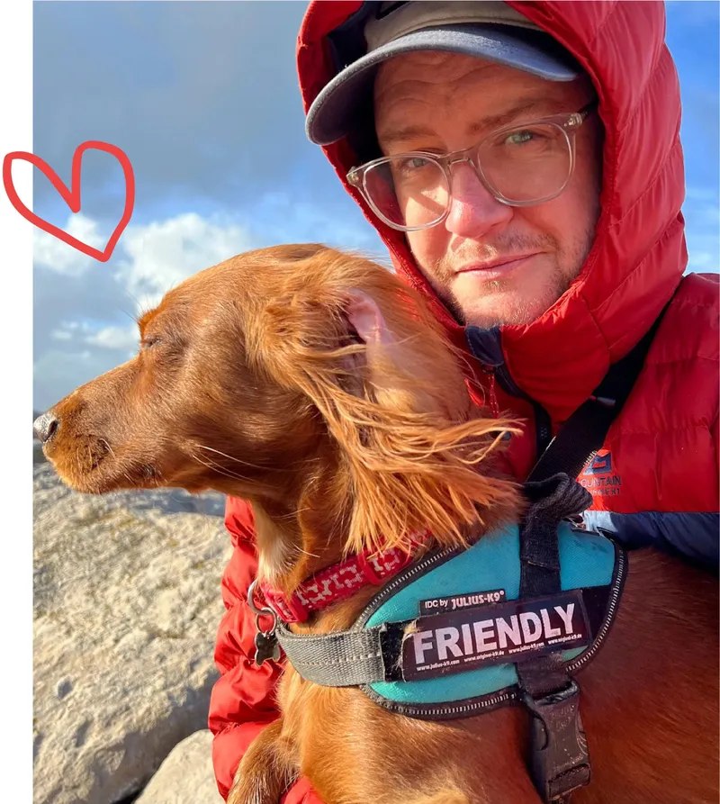 Martin taking a selfie with his dog, wearing a red jacket outdoors